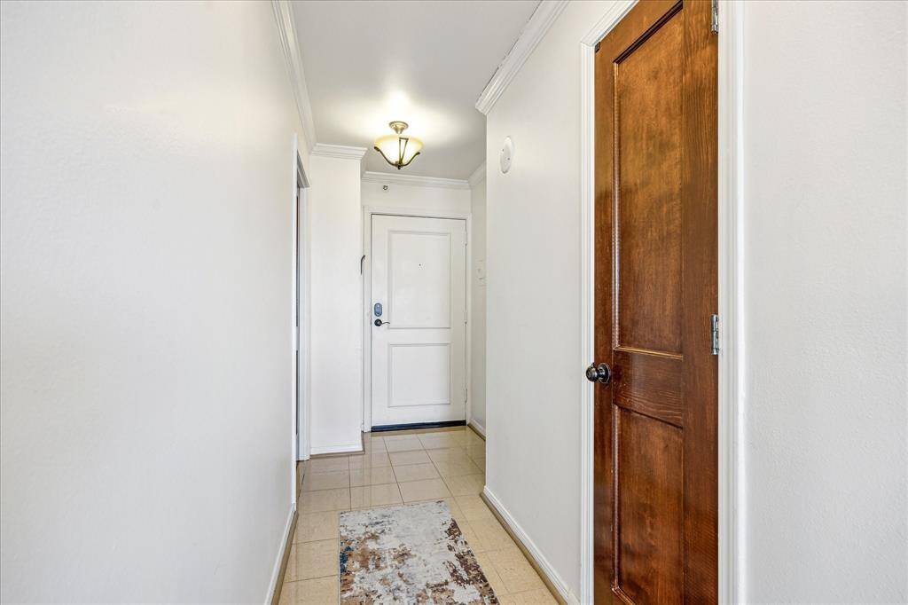 The foyer welcomes you with elegant crown moulding, double pendant lights, a convenient coat closet, and tile flooring.