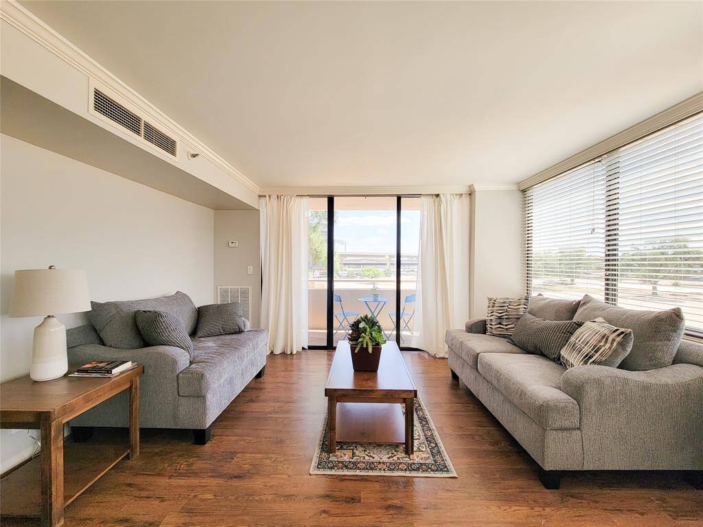 Living area with view to the balcony! Rich, shining laminate flooring! Beautiful window coverings and lots of natural light.