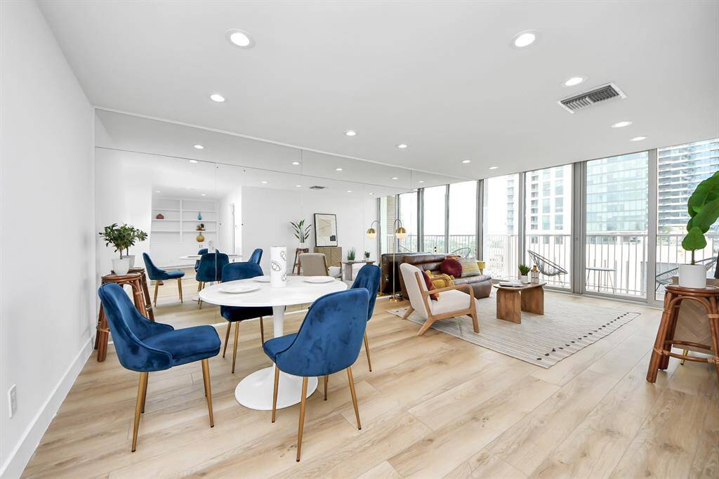 An airy, open-plan space with light oak floors, a full-height mirror wall that enhances brightness.