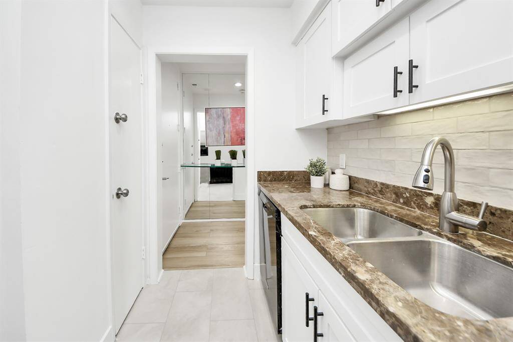 View of the hallway with the front door on the left, neutral walls, and light hardwood floors.