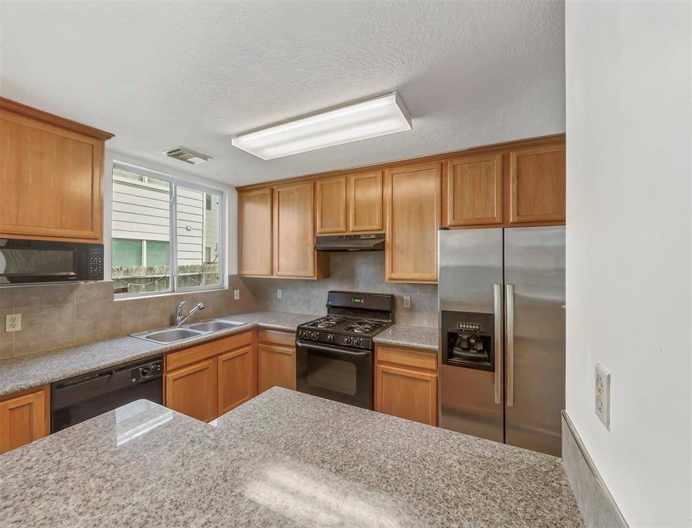 Sunshine streams into this lovely kitchen, illuminating the warm wood cabinets and gleaming countertops. So inviting!
