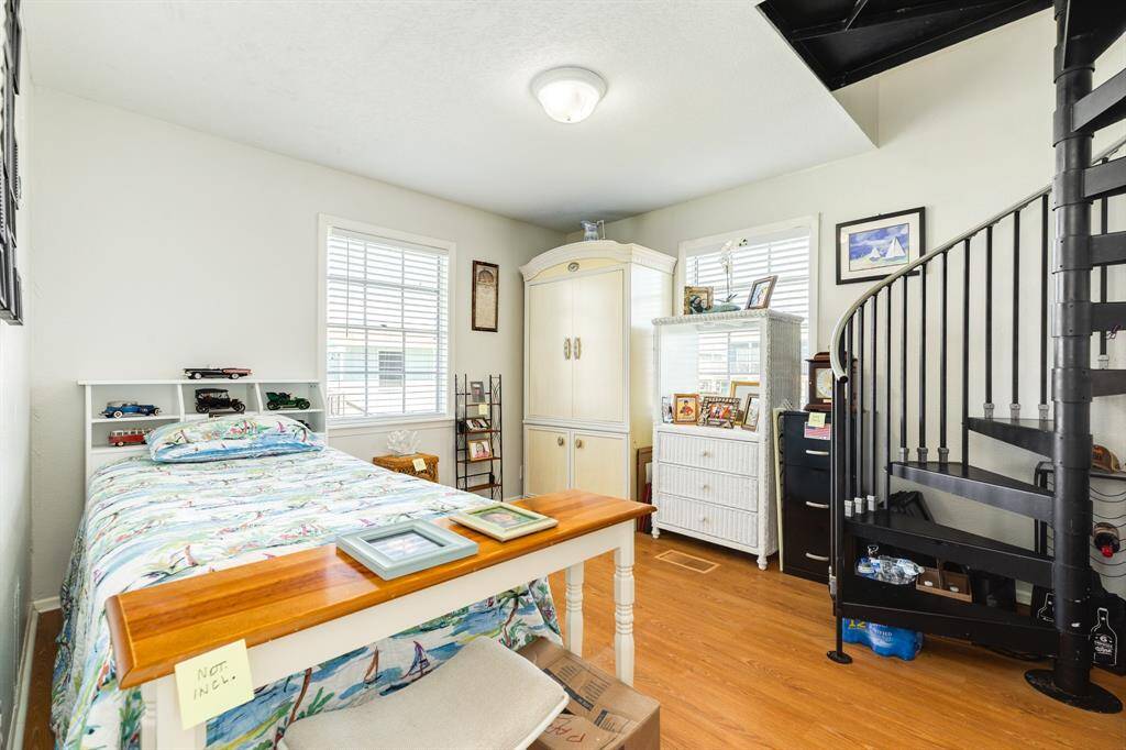This bright bedroom features a spiral staircase that leads directly to the spacious primary suite upstairs.