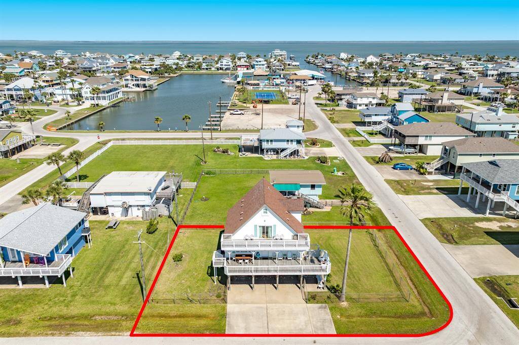 Sweeping aerial angle captures the home in relation to the canal and neighborhood marina. This location blends beachside charm with easy access to boating and bay adventures.