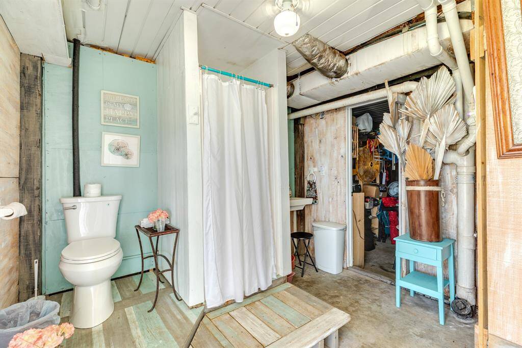 This rustic coastal bath on the ground level is perfect for rinsing off after the beach. Complete with a walk-in shower, toilet, and sink area—plus direct access to storage and utilities.