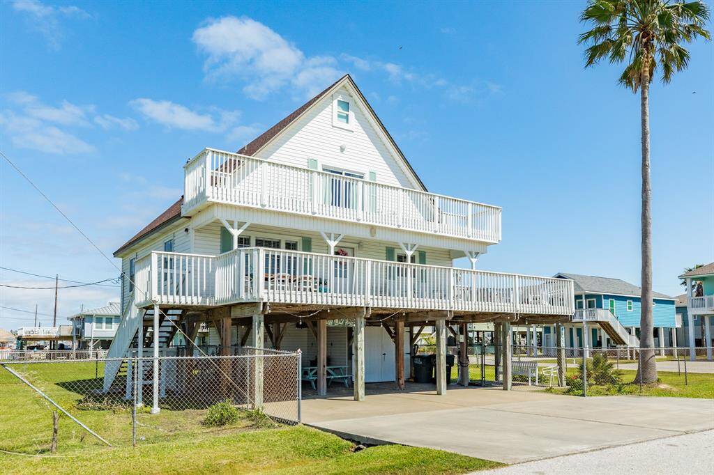This side angle reveals the home’s beautiful architecture and generous decks—ideal for enjoying the sea breeze and hosting guests. A towering palm adds to the tropical appeal.