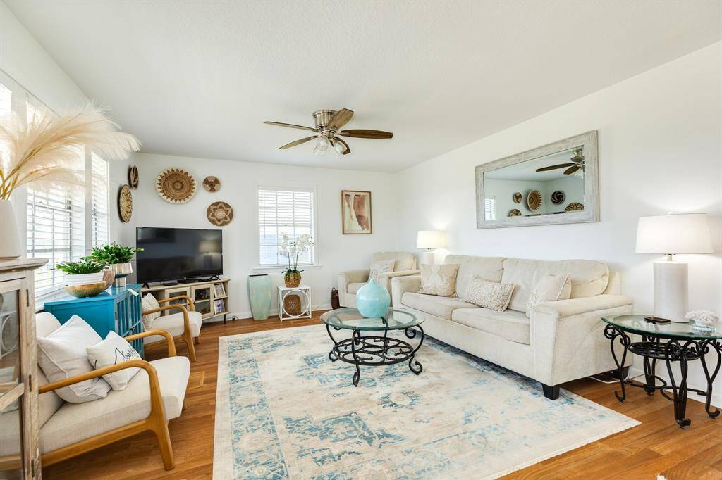 The inviting living area is filled with natural light and coastal charm, featuring plush seating, soothing tones, and stylish decor—perfect for relaxing or entertaining.