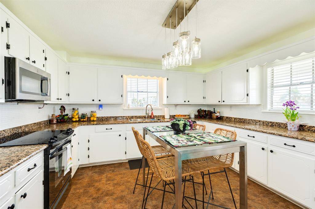 Bright and cheerful kitchen with wrap-around counters and sunny windows.