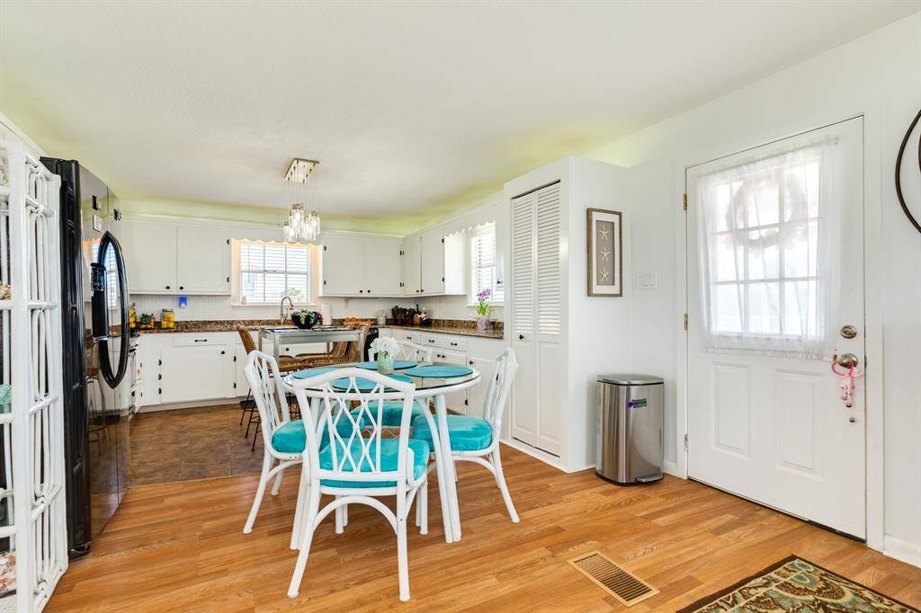 The cozy dining nook and cheerful kitchen feature white cabinetry, granite counters, and pops of turquoise. A great spot to gather for meals or prep your beach day snacks.
