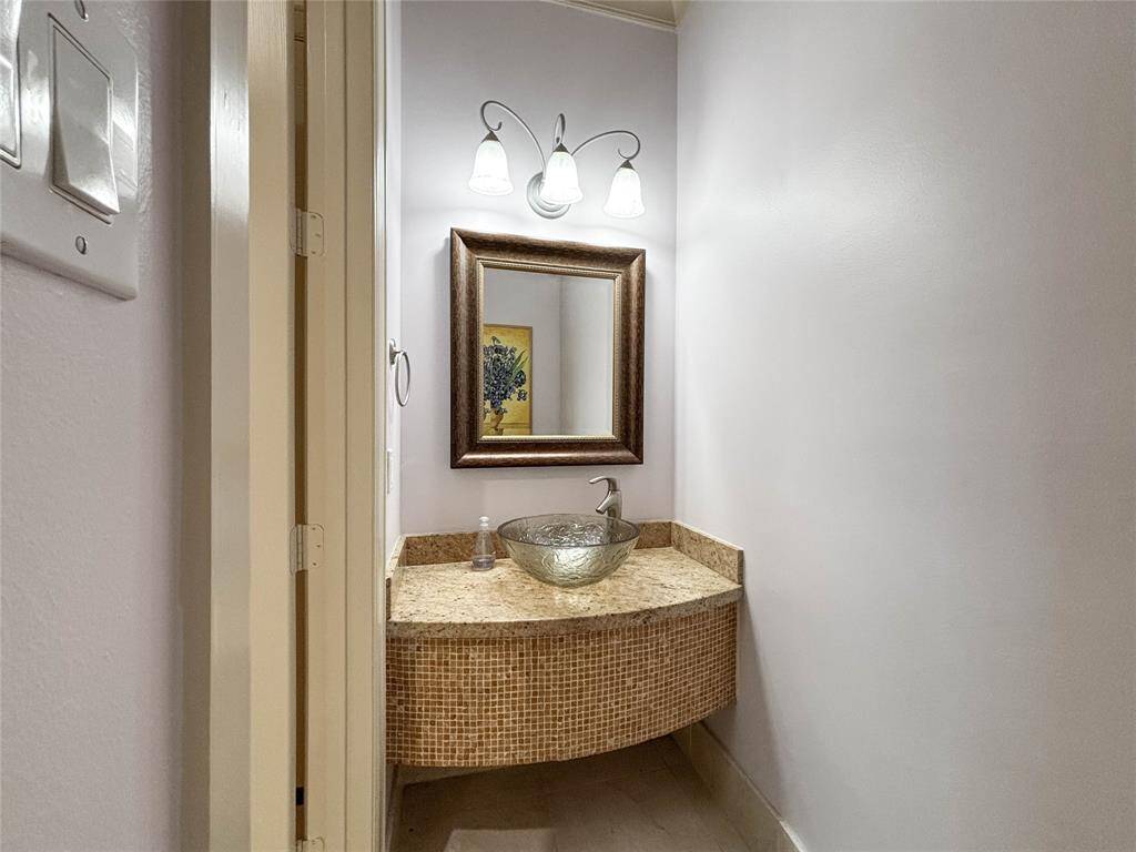 Mosaic tile front vanity with granite countertop are in the Powder Room