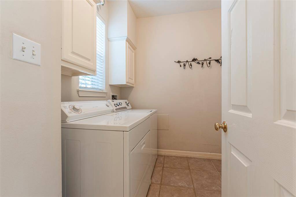 Utility room with tile flooring; washer and dryer included.