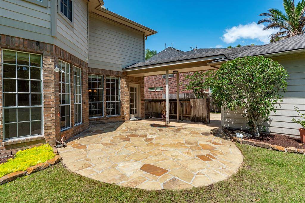 Stone back patio with covered walkway from the garage to the back door.