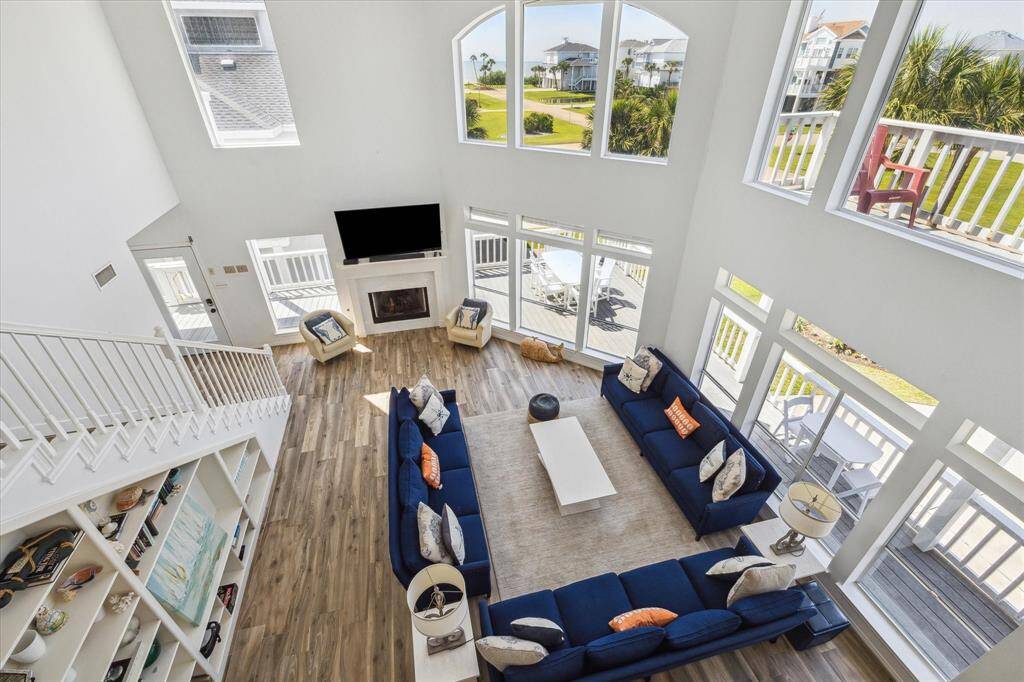 View of the living room from the 2nd floor landing.  The gulf and beach can be seen through the windows.