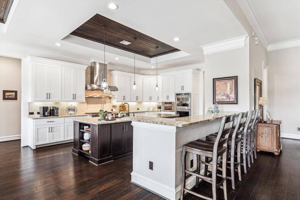The heart of the home is the chef’s kitchen, featuring an oversized island, high-end appliances, a built-in refrigerator, and abundant custom cabinetry—truly a dream for any home cook or host.