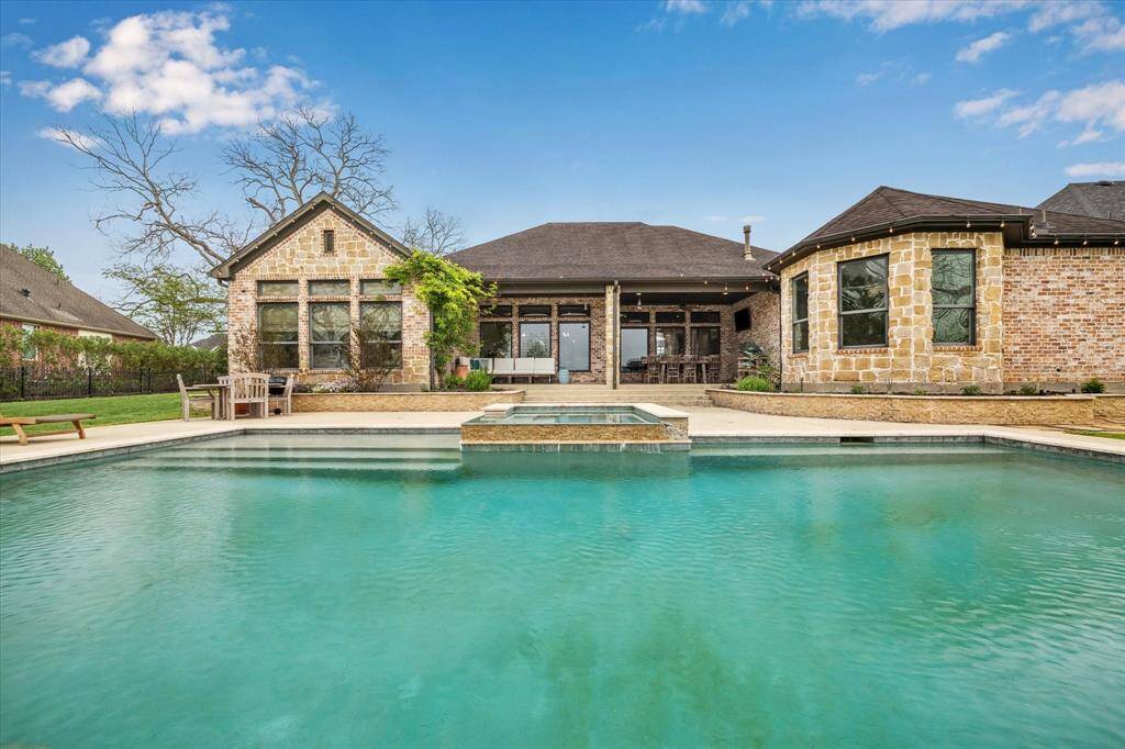 The resort-style backyard features a sparkling pool and spa, tranquil water views, and a cozy outdoor gas fireplace, making it an entertainer’s dream all year long.