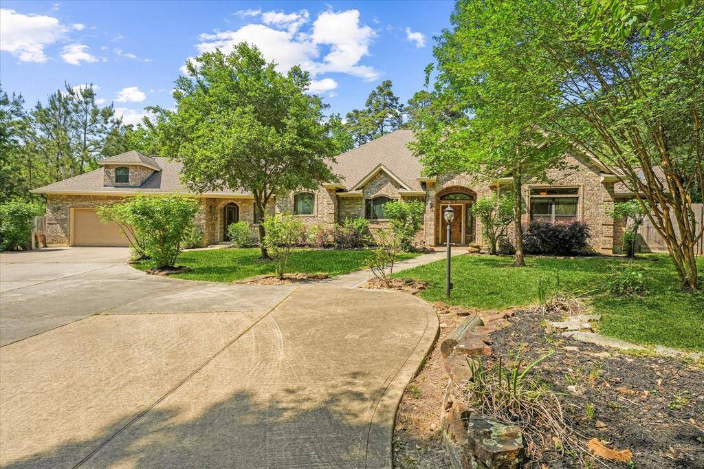 Welcome home! Front view of the home featuring large driveway, well-maintained yard and mature trees, and a serene, peaceful setting.