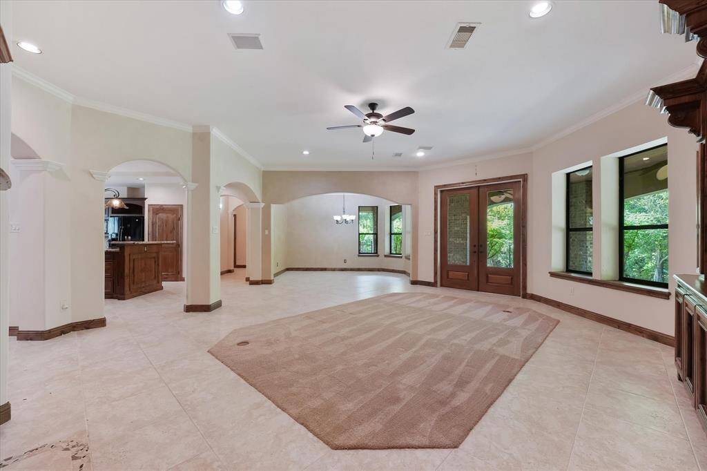 A view of the main living area, looking from the side of the fireplace towards the French-style back doors and the formal dining area.  To the left is the entry to the kitchen.