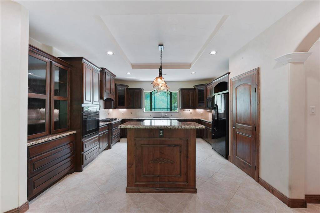 "Head-on" view of the kitchen, showing off the large island, beautiful custom cabinetry, and large drawers for storage.  The door to the right is the walk-in pantry.