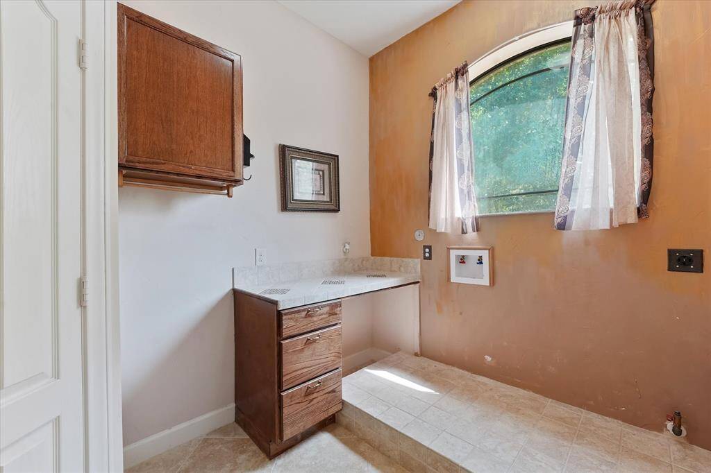 Utility room with built-in pedestal and featuring both gas and electrical dryer connections