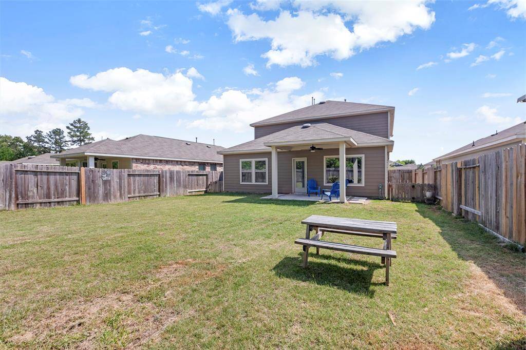 Spacious backyard with a covered patio, ideal for outdoor relaxation and entertaining. The yard is fenced for privacy and features a picnic table for gatherings.