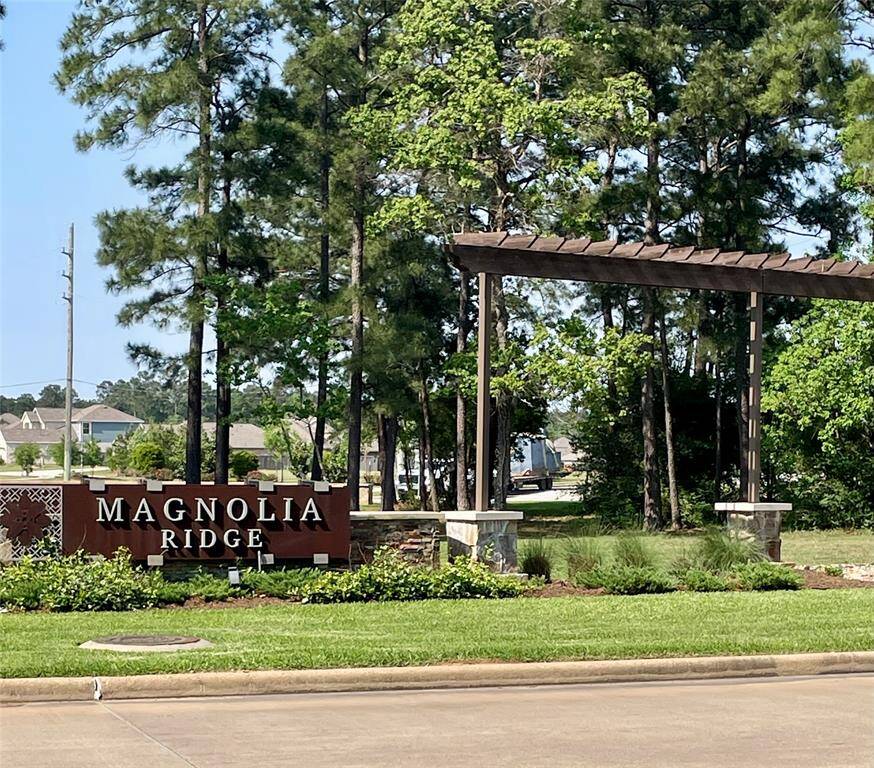 The photo shows the entrance sign for "Magnolia Ridge," a residential community surrounded by trees and greenery, suggesting a serene and natural setting.