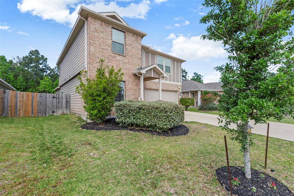 This charming two-story brick home features a well-maintained front yard with shrubs and a small tree. It has a wooden fence, a two-car garage, and a spacious driveway. The exterior offers a blend of brick and siding, creating a welcoming curb appeal.