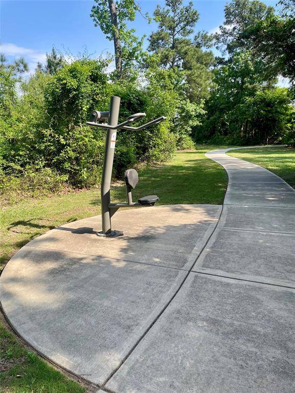 This photo features an outdoor fitness area along a curved walking path, surrounded by lush greenery, offering a serene and active lifestyle opportunity.