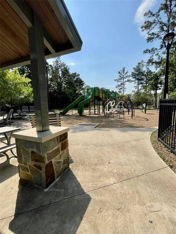 Family-friendly playground with modern equipment, shaded seating, and a safe, fenced area surrounded by trees.