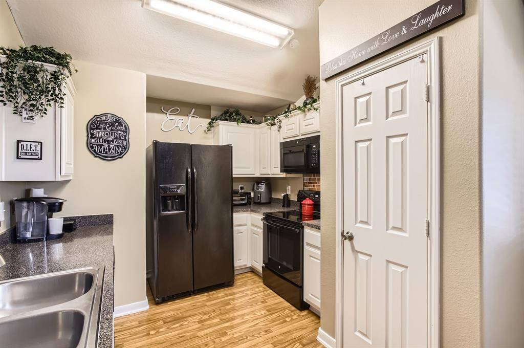 The kitchen offers beautiful wood laminate flooring, bright white cabinetry and all black appliances.