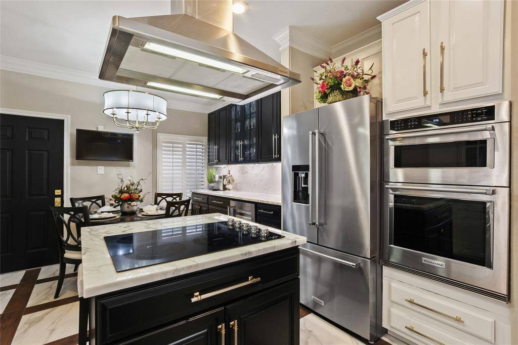 This modern kitchen features sleek stainless steel appliances, a spacious island with a cooktop, and elegant cabinetry. The dining area is cozy and well-lit, perfect for family meals.