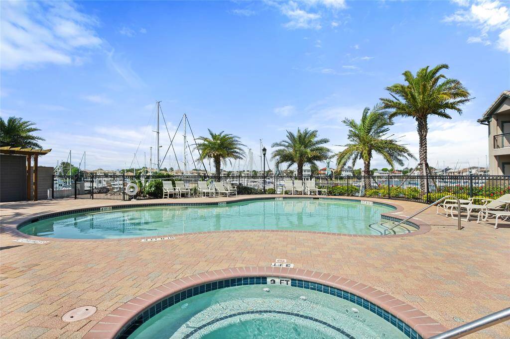 This photo features a serene pool area with a hot tub, surrounded by palm trees and overlooking a marina. Ideal for relaxation and enjoying waterfront views.
