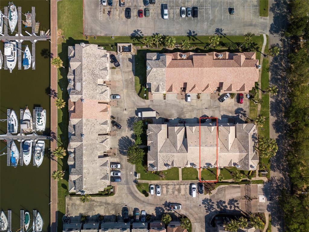 This aerial view shows a townhouse in a well-maintained complex with a marina nearby. The property is highlighted, offering proximity to water and ample parking. Ideal for those seeking a waterfront lifestyle.