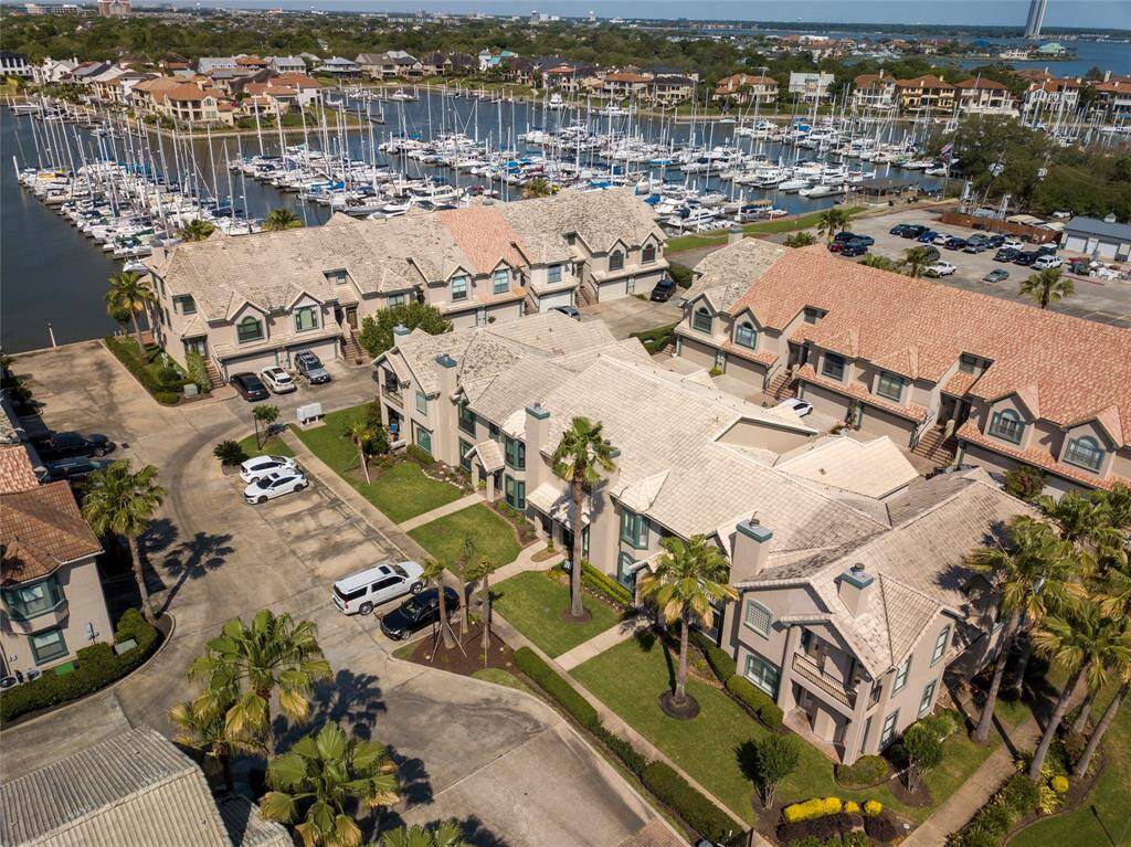 This photo showcases a townhouse with a tiled roof and manicured front lawn, located in a well-maintained complex. It features a additional parking spaces and is near a marina, offering a convenient and picturesque setting.  Subject property noted in red.