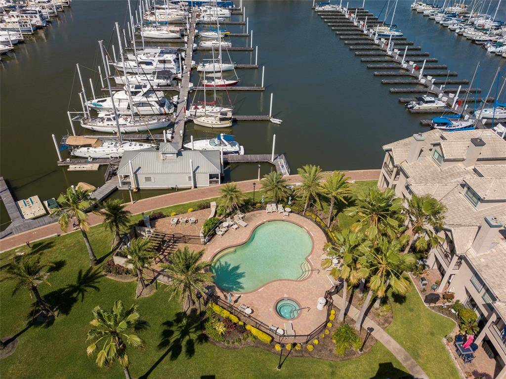 This photo showcases a waterfront property featuring a marina with numerous boats, a beautifully landscaped pool area surrounded by palm trees, and a multi-story residential building, offering a luxurious and serene lifestyle.
