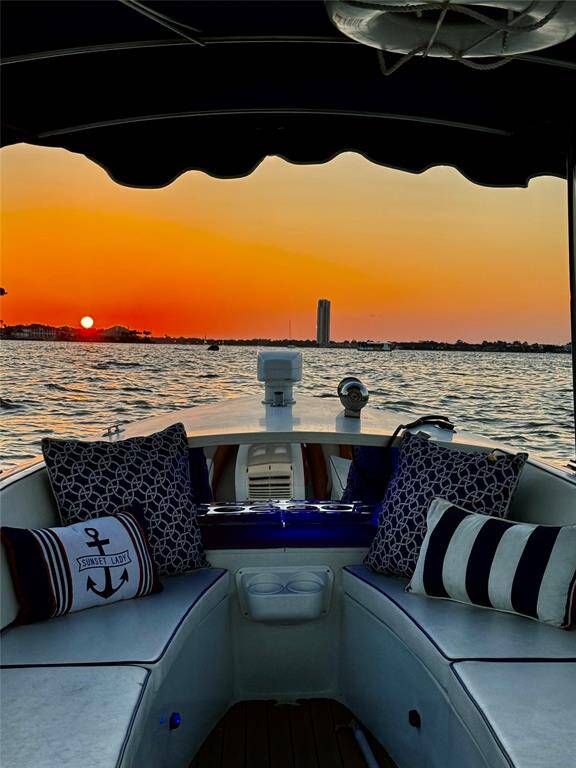 Cozy boat seating with nautical-themed cushions offers a perfect view of a stunning sunset over calm waters. Ideal for enjoying serene evenings on the water.