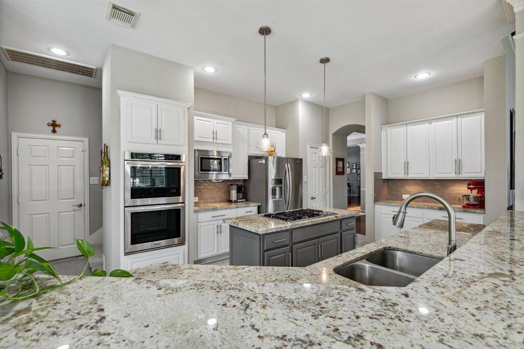 The walk-in pantry is just beyond the refrigerator and the island has terrific storage. Look at the movement in the granite - interesting yet subtle. Just behind the double ovens is a second stairway that leads directly to the game room.