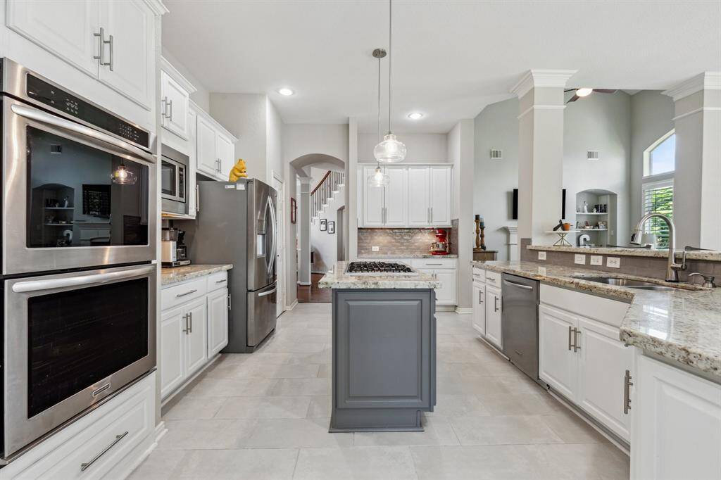 From this view you can see the designer backsplash. It ties together the granite counters and designer colors of the kitchen. Nice pendant lights seal the deal.