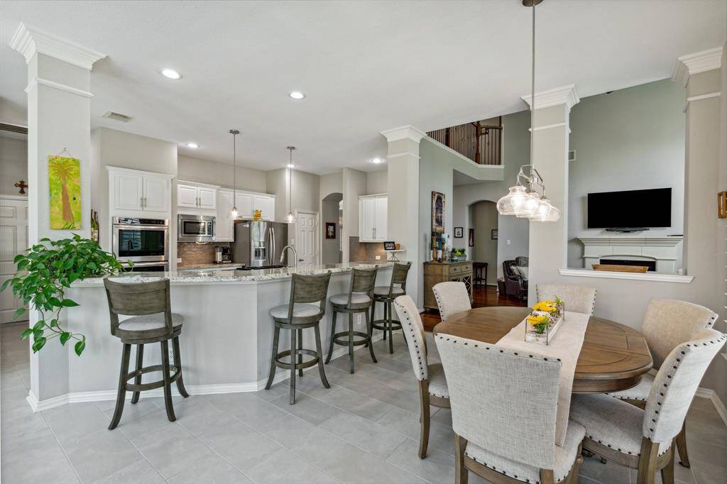 Look at the length of that breakfast bar! The breakfast space is very large and has a coordinating chandelier that matches the pendants in the kitchen. You need to visit this home to FEEL the warmth.