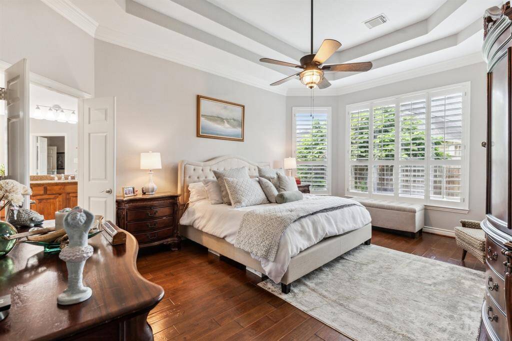 Exquisite primary suite has a six windows covered with plantation shutters. The double tray ceiling give the room a feeling of elegance. Wood flooring provides a warm and dignified look. There is plenty of room for large storage pieces and seating.
