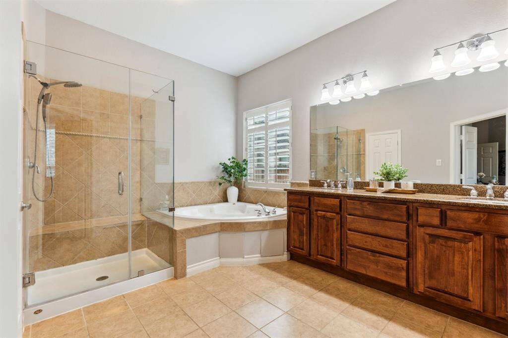 Primary bath has separate shower with new glass enclosures, a separate soaking tub, double vanities and granite counters.
