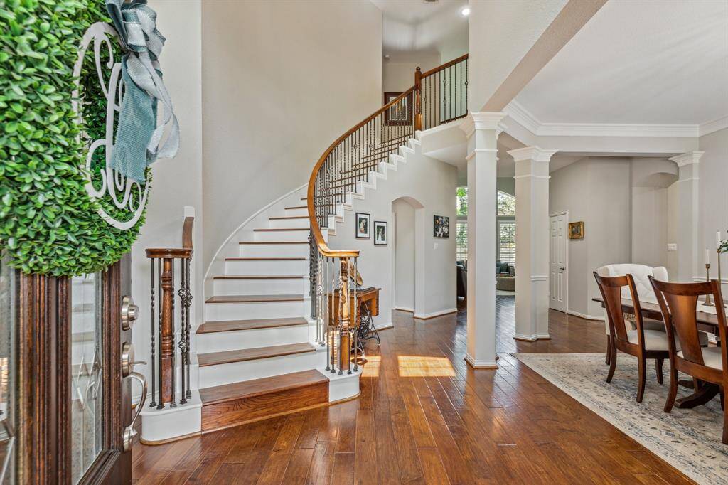 Just imagine greeting your guests here! A grand curved staircase with wood treads (updated by Seller) and a wood landing at the top of the stairs. Columns grace the delineation of the dining room while allowing for open concept living.