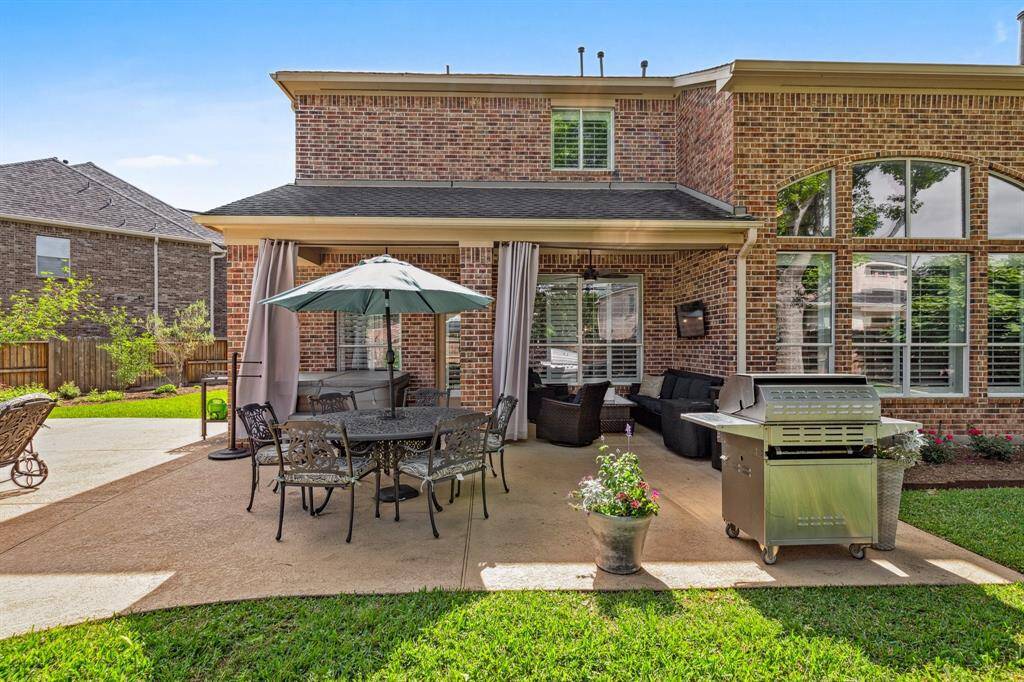 A view of the back covered porch with draperies and room for plenty of seating. Enlarged slab allows for multiple seating options.
