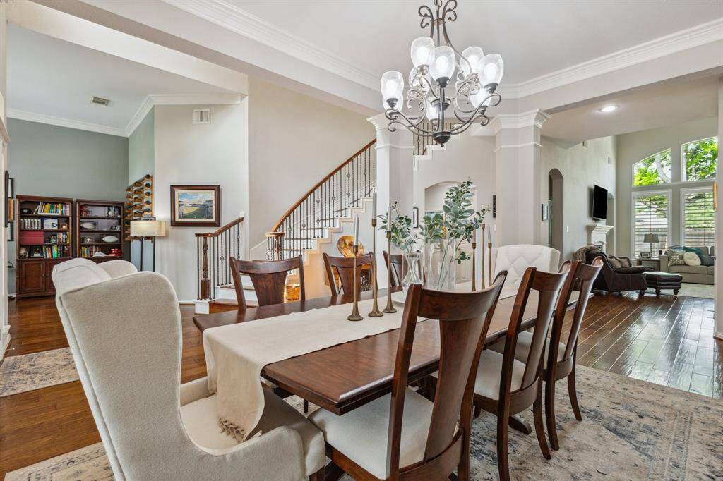 A view from the dining space into the home office and spacious living room. Gracious chandelier enhances the charm of the space. Notice the crown molding on both the ceiling and the columns.