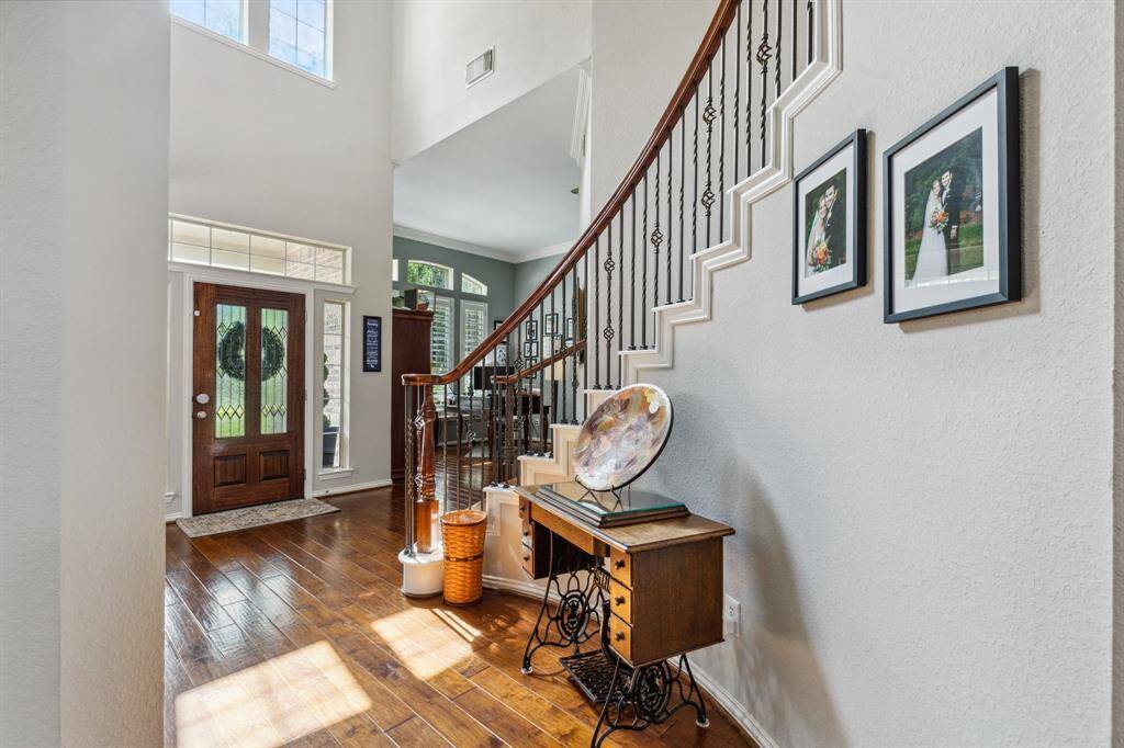 Looking back at the foyer and leaded glass front door is flanked by sidelights and transom windows. The curved staircase accents the two-story ceilings of the foyer.