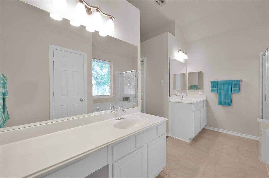 Primary bathroom features double vanities and his and her closets.