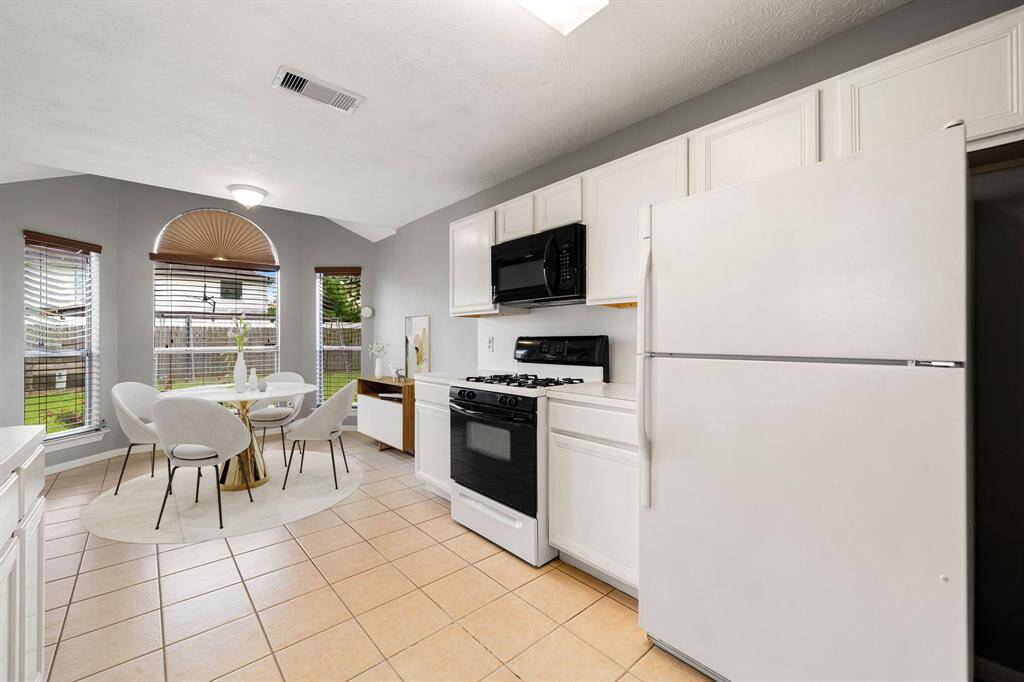 Bright and airy kitchen with crisp white cabinetry, a double sink, and an open view into the living area. The adjacent breakfast nook is surrounded by large windows that fill the space with natural light, perfect for morning coffee or casual dining. *Virtually Staged