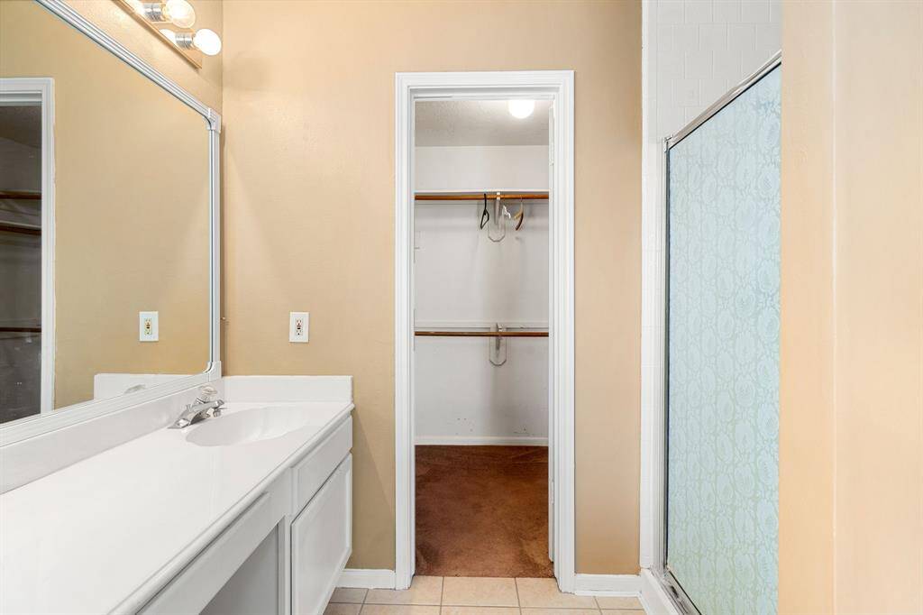 This additional view of the primary bath showcases a walk-in shower, the large double sink and walk-in closet.