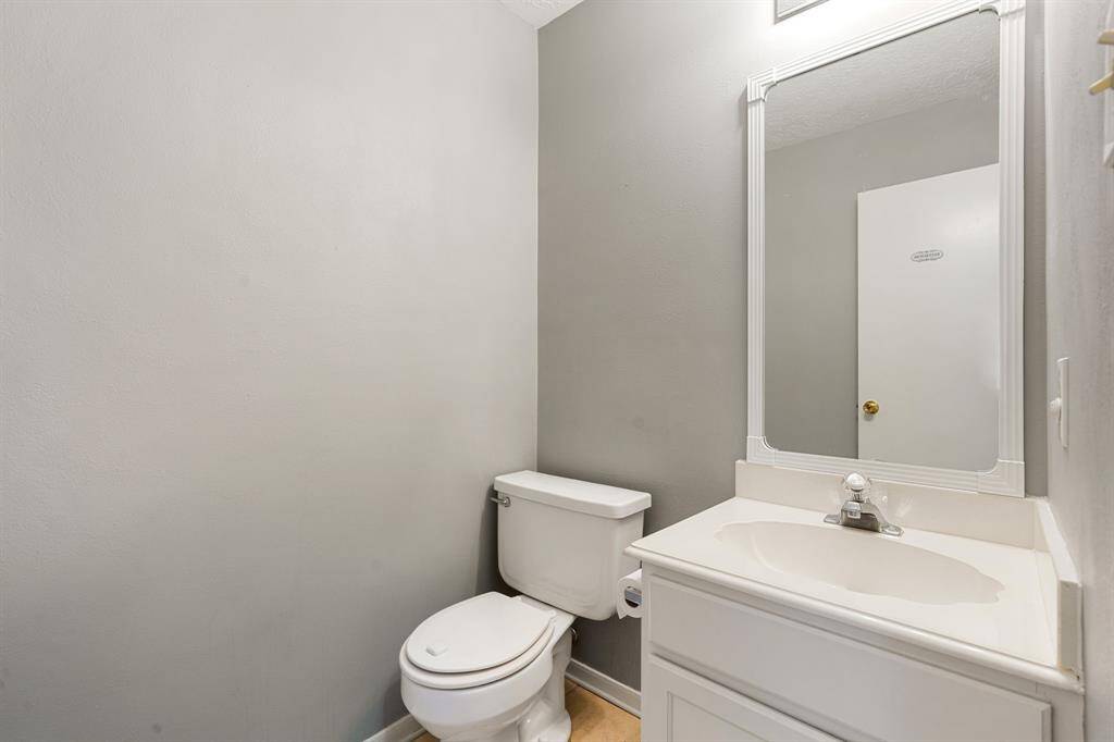 Cozy half-bath featuring a sleek vanity with integrated sink, a large framed mirror, and neutral tones, perfect for guests or quick fresh-ups.