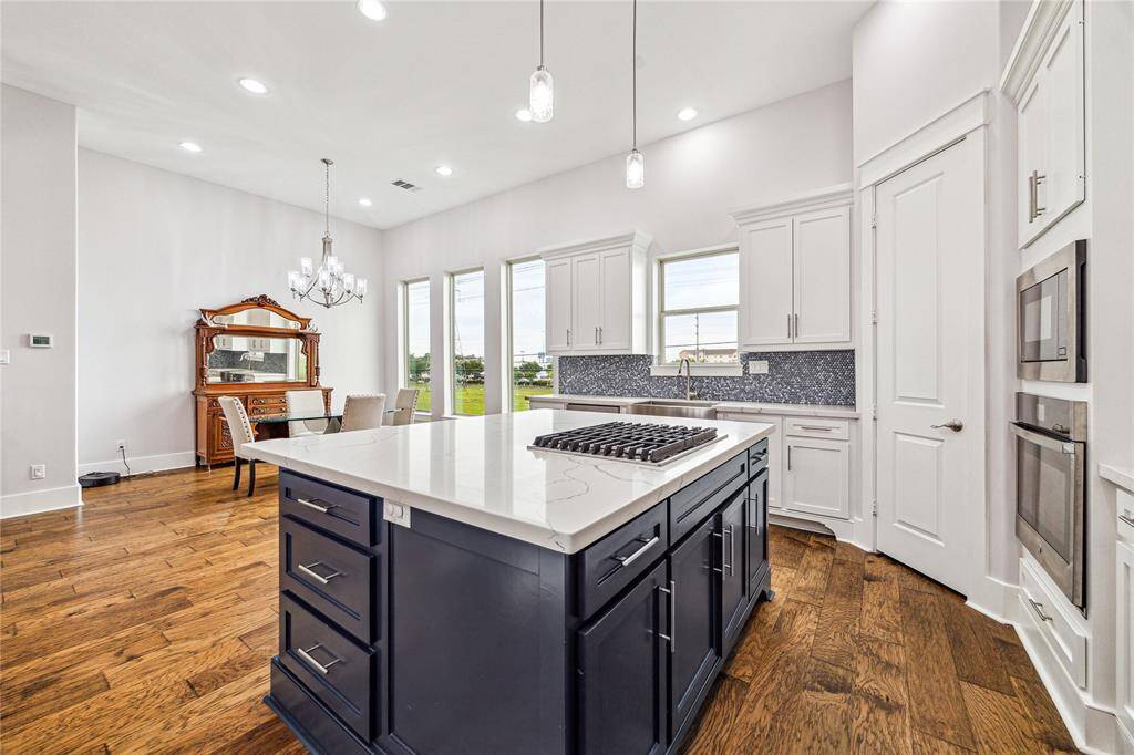 A sleek gas cooktop on the spacious island offers both style and practicality, while double ovens nearby provide the perfect setup for preparing meals with ease.