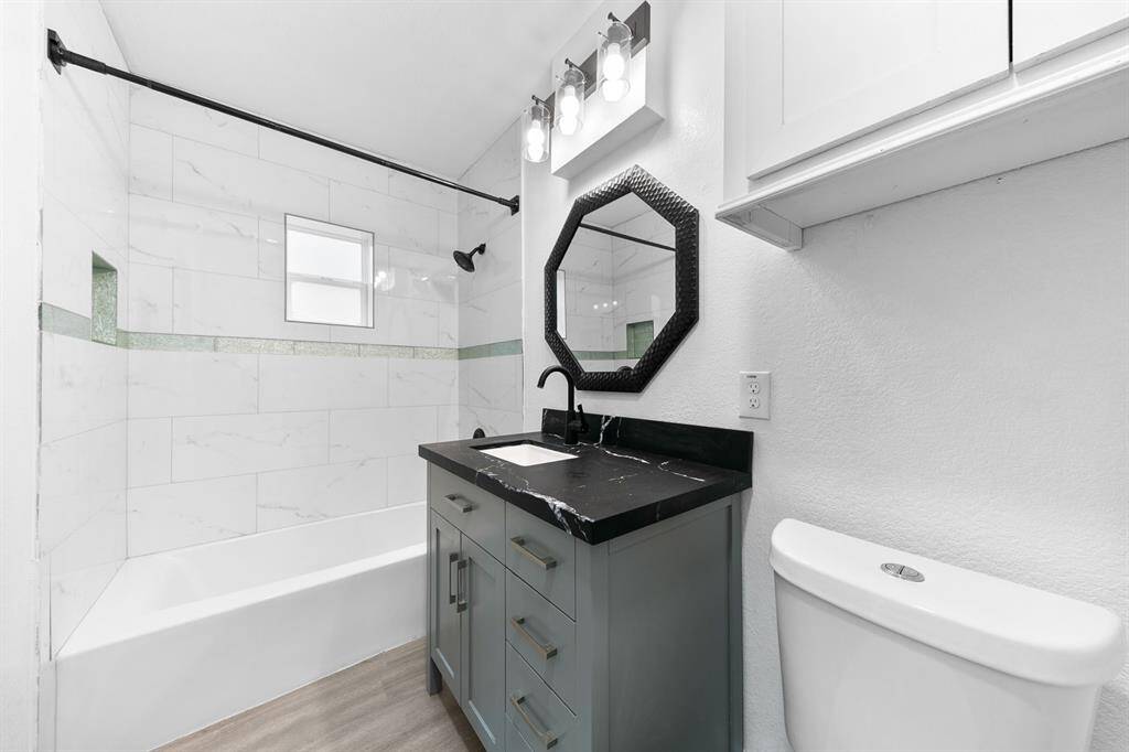 Primary bathroom featuring elegant leather quartz countertops and a convenient shower/tub combo—perfect for relaxation and practicality