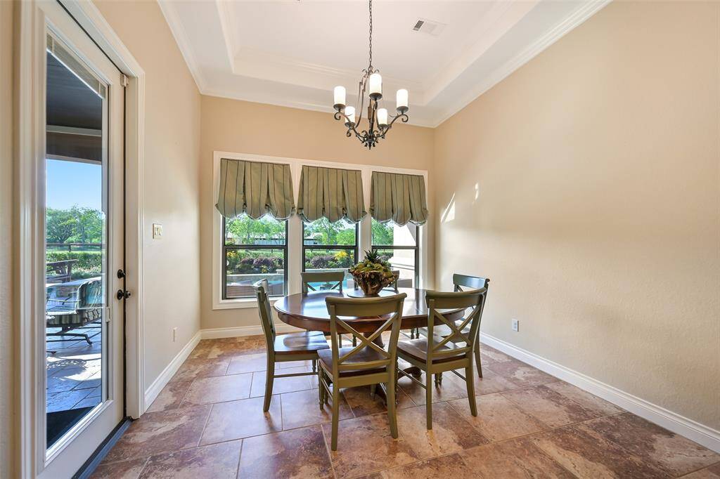 Bright dining area featuring large windows with custom green valances. The room has a chandelier, tile flooring, and access to an outdoor patio.